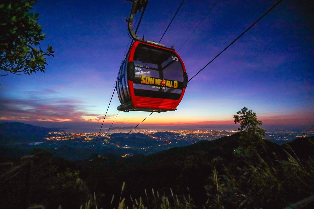 Cabin cáp treo Bà Nà lơ lửng trên núi, phía dưới là ánh đèn thành phố lúc hoàng hôn
