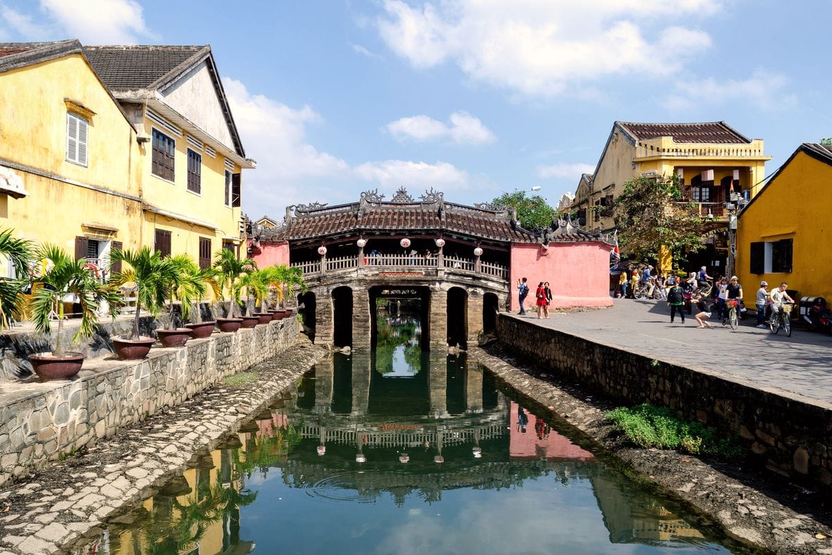 Chùa Cầu Hội An soi bóng xuống dòng kênh, hai bên là nhà cổ tường vàng