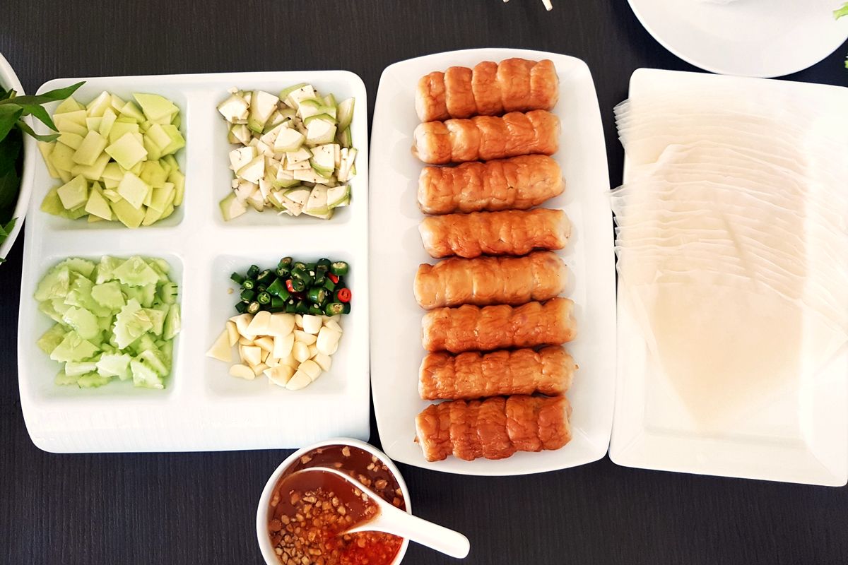 Đĩa nem nướng cùng bánh tráng, rau sống, dưa leo và chén nước chấm